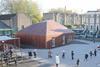 The building sits in the corner of the playground like a toy house, wrapped with cedar floorboards.