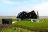 The faceted roof floats above a glazed ground floor, partially sunk into the surrounding dunes..