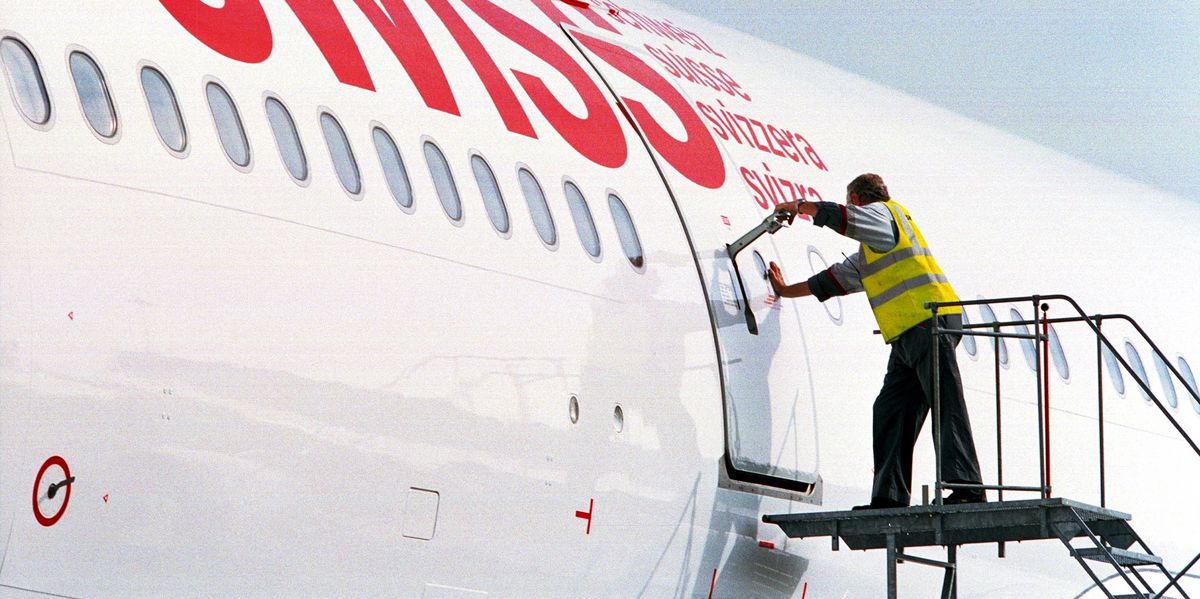 FILE --- An employee of Swiss International Air Lines is to open a door of a plane waiting at the airport in Zurich-Kloten, 2 october 2002.  SwitzerlandÕs national carrier, Swiss International Airlines, is to axe 700 jobs and cut its fleet by 20 aircraft in a bid to stay afloat. Announcing the cuts on Tuesday, February 25 2003, in Zurich, chief executive Andre Dose said the cuts were in response to weak markets. (KEYSTONE/Martin Ruetschi)